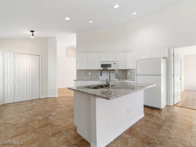 kitchen featuring sink, tasteful backsplash, light stone counters, white appliances, and white cabinets