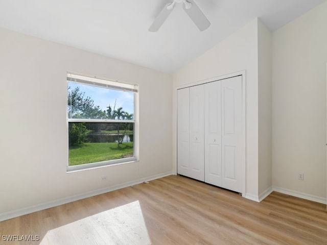 unfurnished bedroom with ceiling fan, lofted ceiling, light wood-type flooring, and a closet