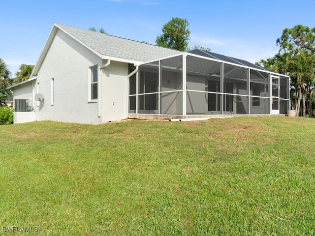 back of property featuring a lawn, glass enclosure, and central air condition unit