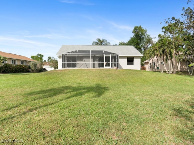 rear view of property featuring a lawn and glass enclosure