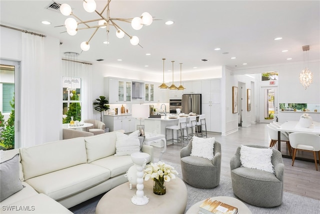 living room featuring sink, light hardwood / wood-style flooring, and an inviting chandelier