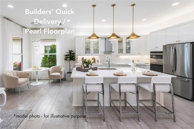 kitchen featuring a breakfast bar area, light hardwood / wood-style flooring, stainless steel appliances, and wall chimney range hood