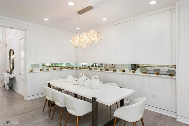 dining space with hardwood / wood-style flooring, crown molding, and a chandelier