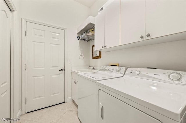 clothes washing area with sink, light tile patterned floors, cabinets, and independent washer and dryer