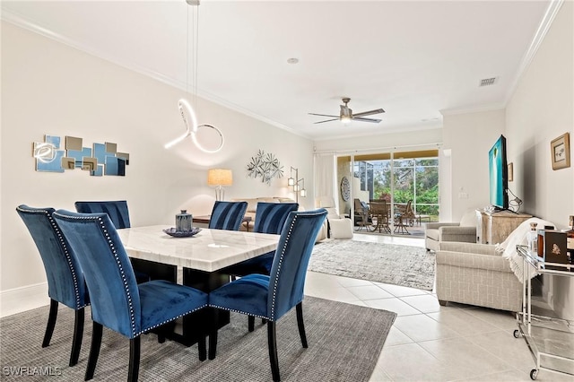 tiled dining space with ceiling fan and ornamental molding