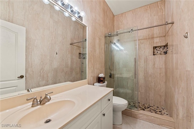 bathroom with tile patterned floors, toilet, vanity, and tiled shower