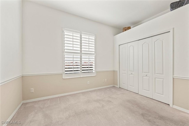 unfurnished bedroom with light colored carpet and a closet