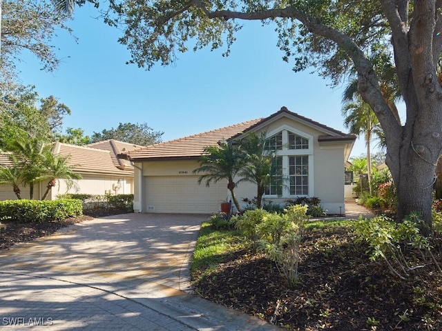 view of front facade featuring driveway, stucco siding, an attached garage, and a tiled roof