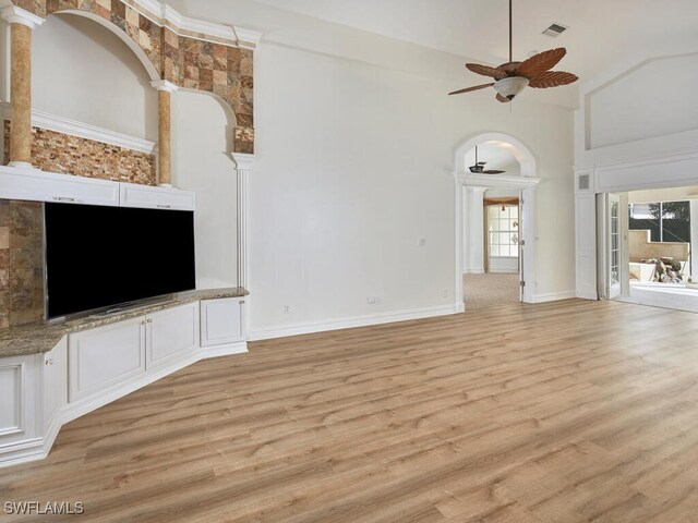 unfurnished living room with ceiling fan, light hardwood / wood-style floors, and a high ceiling