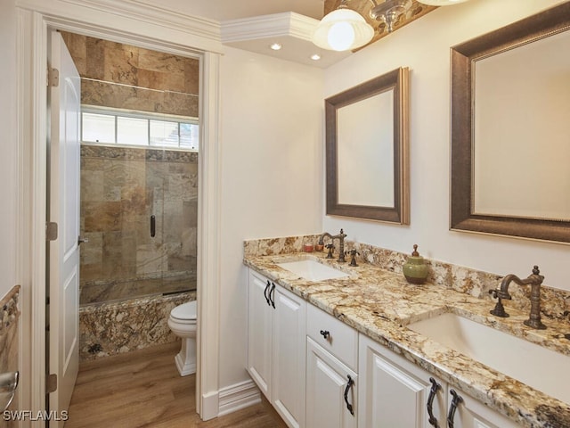 bathroom with wood finished floors, double vanity, combined bath / shower with glass door, and a sink