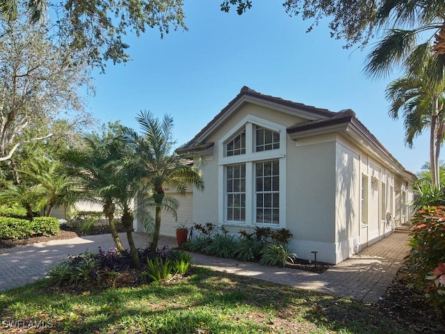 view of side of home with decorative driveway and an attached garage