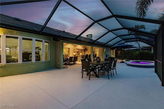 patio terrace at dusk with glass enclosure and an in ground hot tub