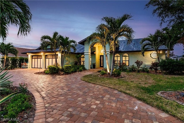 mediterranean / spanish house featuring a garage and a lawn