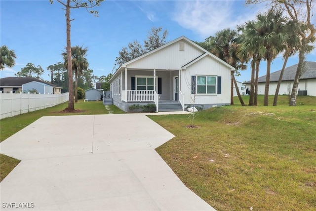 view of front facade featuring concrete driveway, a porch, a front lawn, and fence