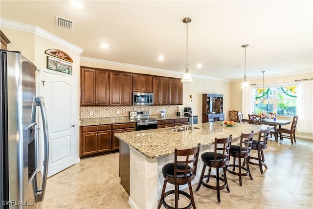 kitchen with sink, a kitchen breakfast bar, pendant lighting, a center island with sink, and appliances with stainless steel finishes