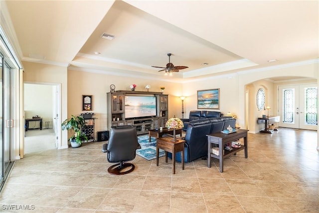 living room with a tray ceiling, ceiling fan, french doors, and crown molding