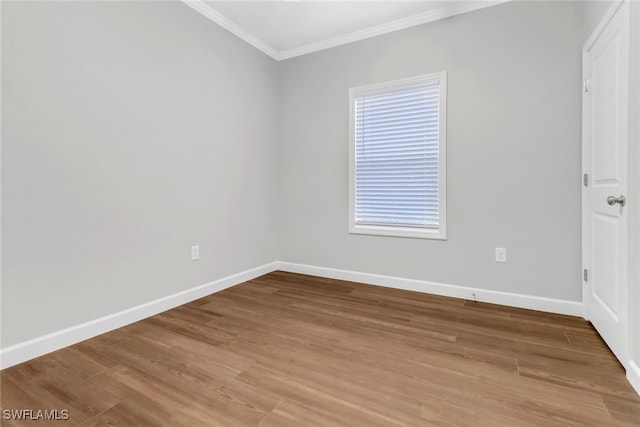 spare room featuring baseboards, ornamental molding, and wood finished floors