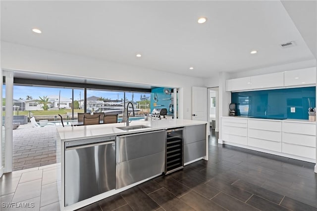 kitchen with dishwasher, sink, beverage cooler, a center island with sink, and white cabinets