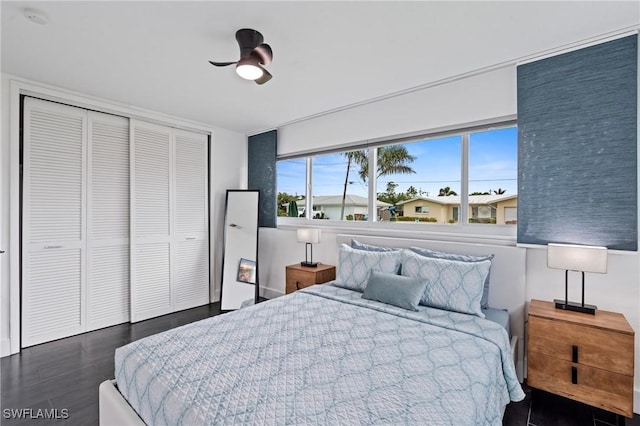 bedroom with dark hardwood / wood-style flooring, ceiling fan, and a closet