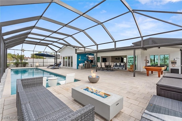 view of pool featuring glass enclosure, a patio, and an outdoor living space with a fire pit