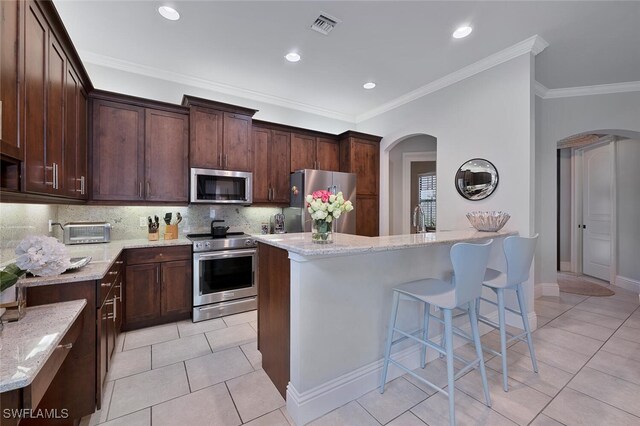 kitchen featuring light stone countertops, a kitchen island, stainless steel appliances, light tile patterned floors, and crown molding