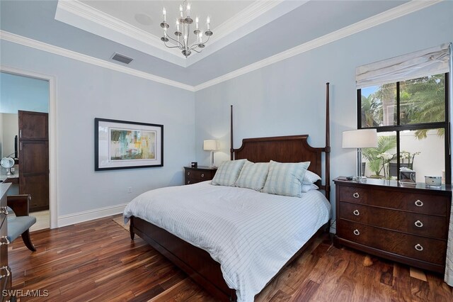 bedroom with crown molding, dark hardwood / wood-style floors, a tray ceiling, and a notable chandelier