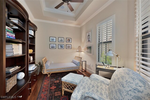 sitting room featuring ceiling fan, a tray ceiling, dark hardwood / wood-style flooring, and crown molding