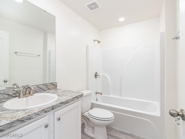 full bathroom featuring toilet, vanity, hardwood / wood-style flooring, and shower / bathtub combination