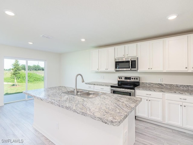 kitchen featuring stainless steel appliances, white cabinets, sink, and an island with sink