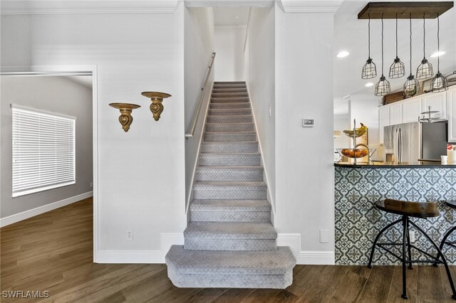 staircase with crown molding and hardwood / wood-style floors