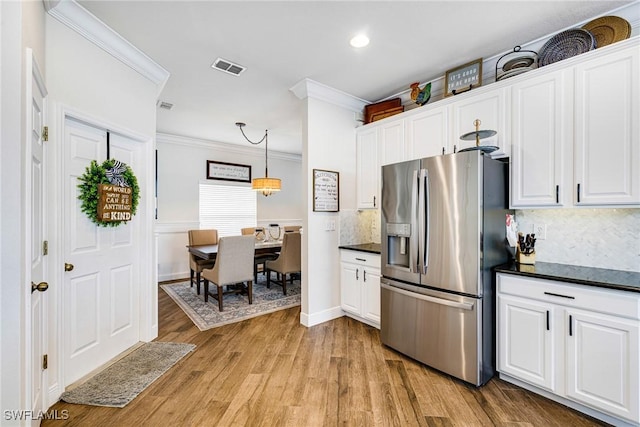 kitchen featuring decorative backsplash, white cabinets, and stainless steel fridge