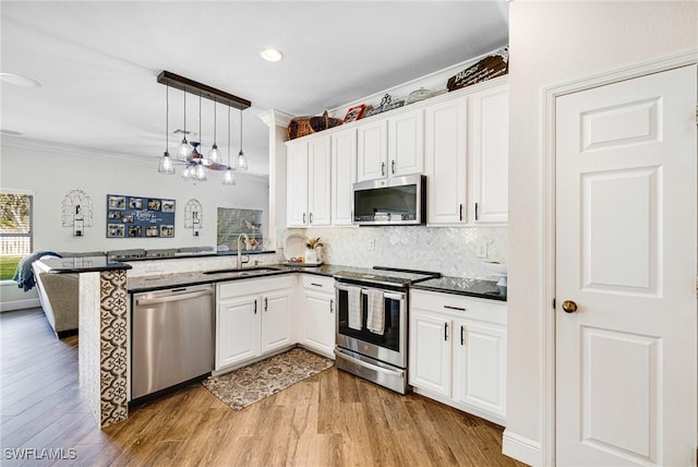 kitchen with white cabinets, stainless steel appliances, sink, hanging light fixtures, and kitchen peninsula