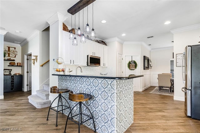 kitchen with kitchen peninsula, a kitchen breakfast bar, stainless steel appliances, and pendant lighting