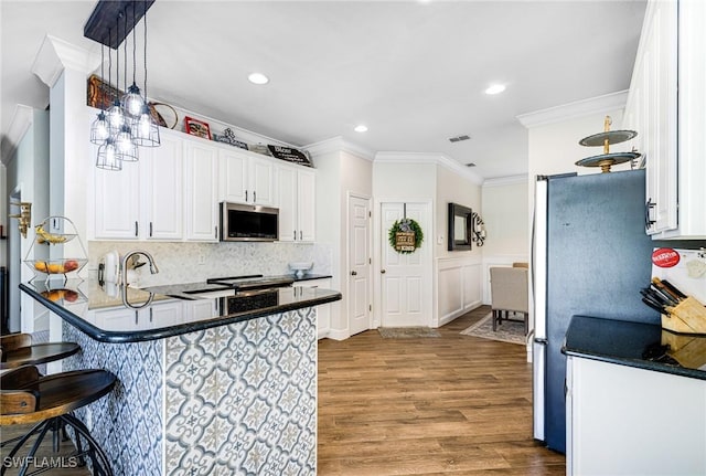 kitchen with stainless steel appliances, decorative light fixtures, a kitchen breakfast bar, crown molding, and white cabinets