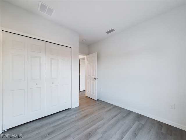 unfurnished bedroom with light wood-type flooring and a closet