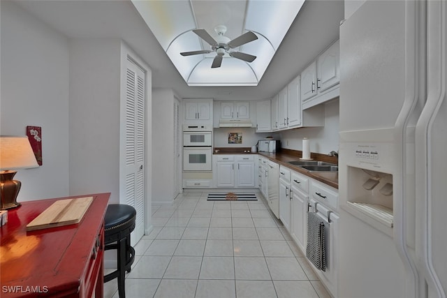 kitchen featuring white cabinetry, light tile patterned flooring, white appliances, and sink