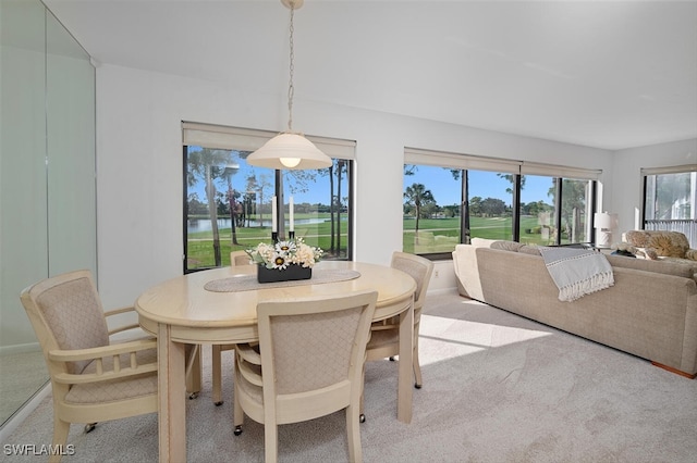 carpeted dining area featuring a water view