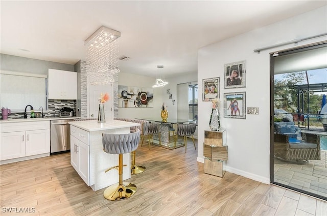 kitchen with white cabinetry, a center island, stainless steel dishwasher, and sink