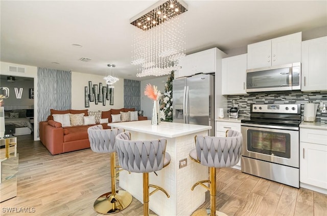 kitchen featuring appliances with stainless steel finishes, backsplash, light hardwood / wood-style flooring, and white cabinetry