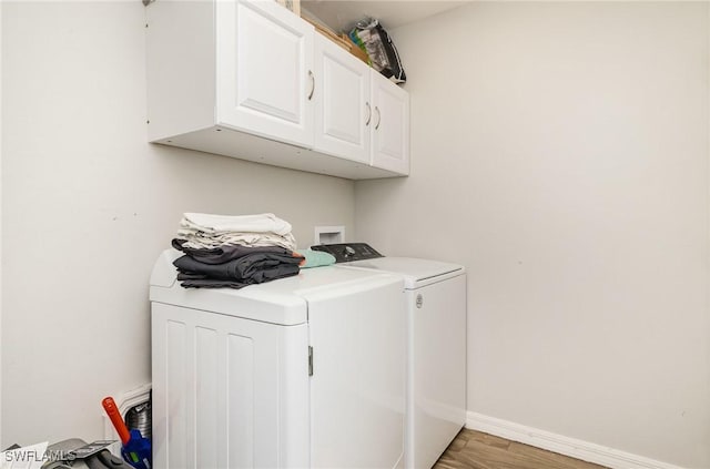 clothes washing area with cabinets, hardwood / wood-style floors, and separate washer and dryer