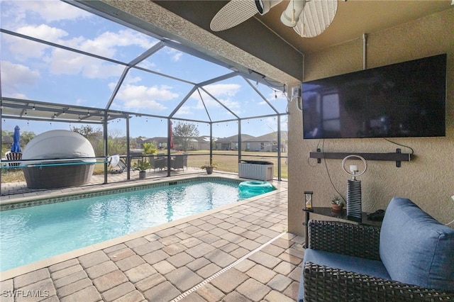 view of swimming pool with ceiling fan, a patio, and glass enclosure