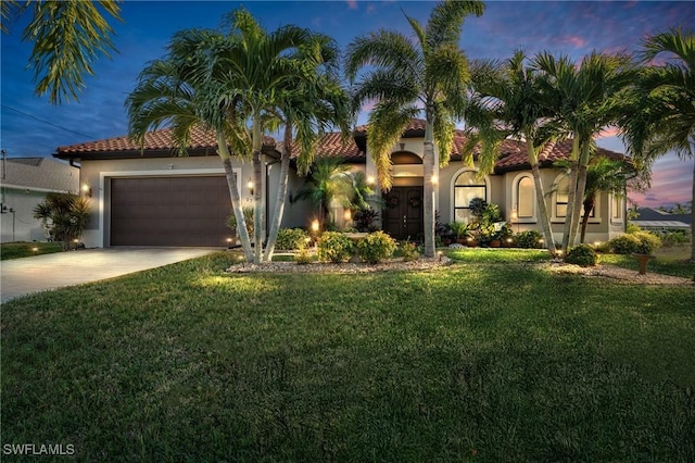 mediterranean / spanish-style house featuring a garage and a yard