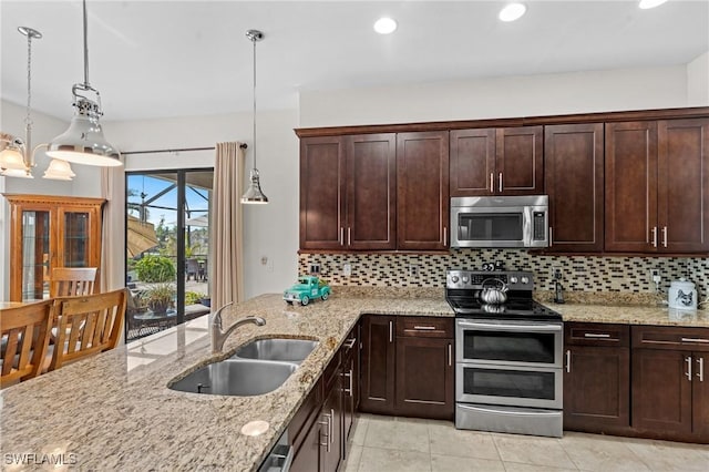 kitchen with sink, decorative light fixtures, stainless steel appliances, light stone countertops, and decorative backsplash