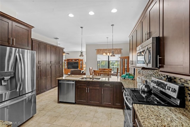 kitchen with pendant lighting, stainless steel appliances, and light stone countertops