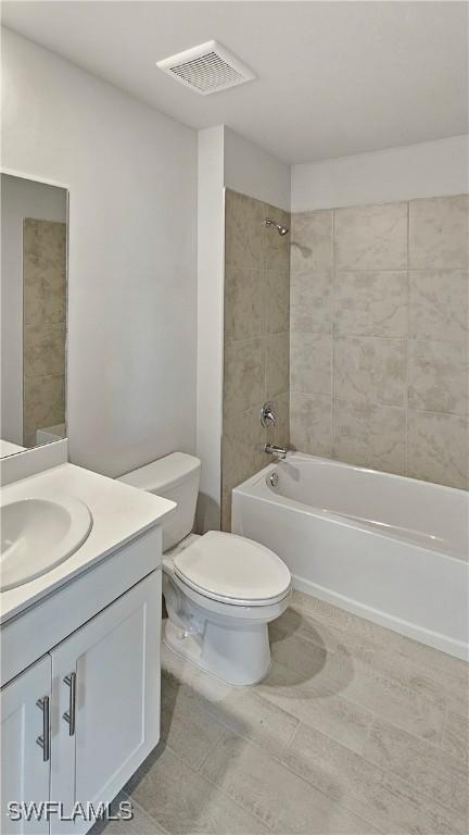 full bathroom with vanity, tiled shower / bath combo, and toilet