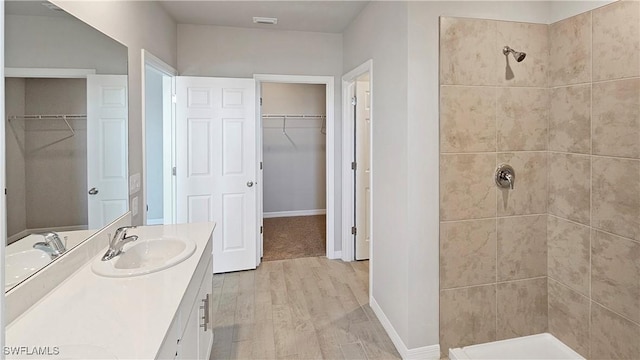 bathroom featuring a tile shower, vanity, and hardwood / wood-style flooring