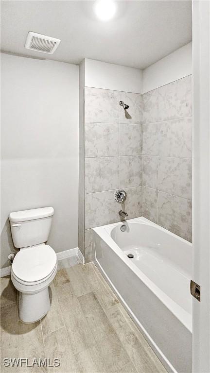 bathroom featuring tiled shower / bath combo and toilet