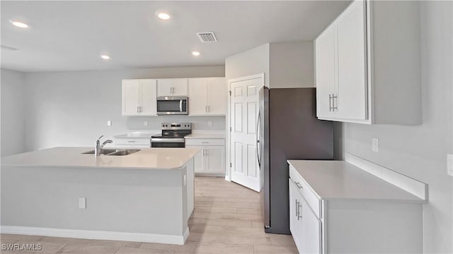 kitchen with sink, white cabinetry, stainless steel appliances, and light wood-type flooring