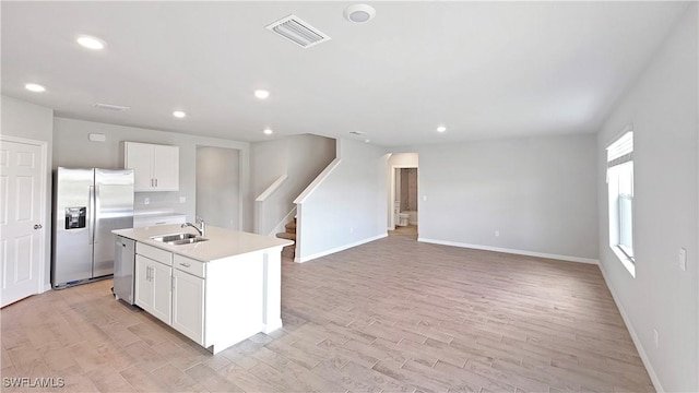 kitchen with sink, stainless steel appliances, light hardwood / wood-style floors, a center island with sink, and white cabinets