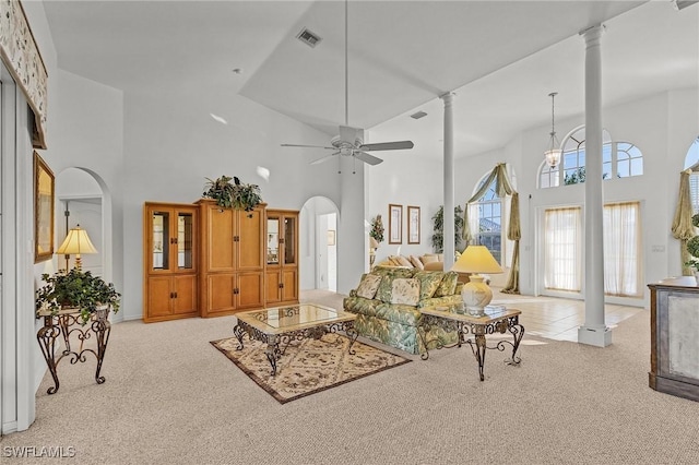 living room featuring light carpet, a towering ceiling, and ornate columns